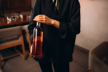 Close up of cute young liquor store assistant holding and examining a bottle of red wine. The woman is standing in old cellar and smiling
