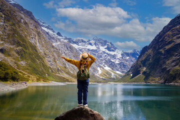Happy young woman  look on the mountain landscape. Travel and active life concept  as Adventure travel in the mountains region in lake marian  fiordland national park - obrazy, fototapety, plakaty