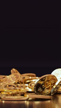 Vertical video of a bunch of golden bitcoin coins falling to the ground from above on a dark background in realistic slow motion 3D animation. Cryptocurrency, 2p2 exchange and blockchain concept