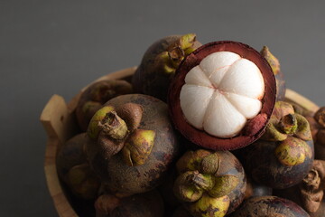 Cut open mangosteen on bamboo base. Mangosteen is popular as Queen of fruit that that has many...