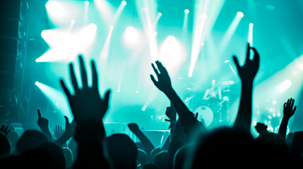 Concert crowd with raised hands, stage lights, live music event.
