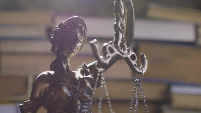 Statue of themis or lady justice. Femida on books background. Lawyer, law library concept