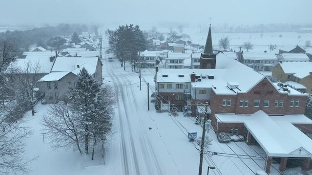 Small town during blizzard in USA. Church and houses during snow flurries. Aerial in winter.