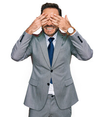 Middle age man wearing business clothes covering eyes with hands smiling cheerful and funny. blind concept.