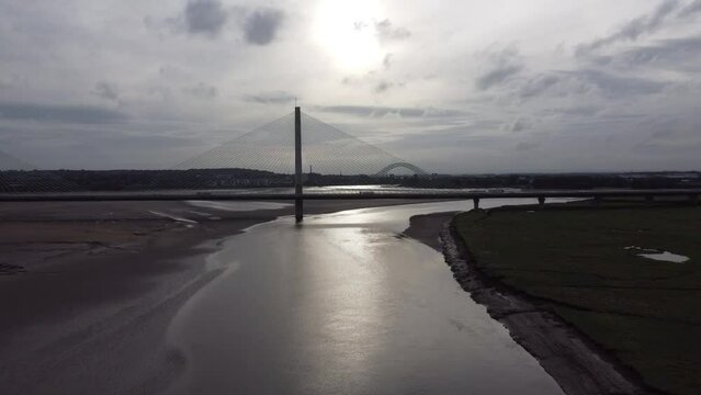 Drone footage of the Mersey Gateway Bridge with a river flowing underneath it.