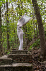 sexy elegant adult woman standing as living statue, her body wrapped in long skin tight white dress, highlighting body shapes, in green spring forest on a brick pedestal, work of art