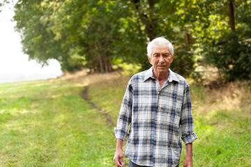Portrait of senior man standing in the park on a sunny day