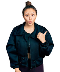 Young hispanic girl wearing sportswear surprised pointing with hand finger to the side, open mouth amazed expression.