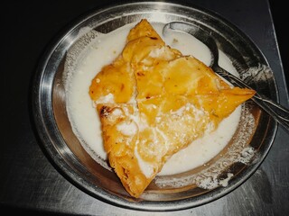A Crispy Golden Brown Samosa Pie Served on a Plate with a Dollop of Yogurt The Samosa Pie is Filled With a Savory Mixture of Potatoes Peas and Spices and it is Deep Fried Until Golden Brown