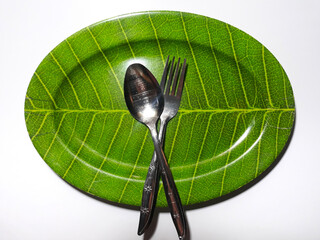 Empty green plate leaf pattern theme with spoon and fork isolated white background