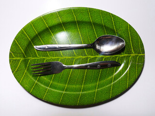Empty green plate leaf pattern theme with spoon and fork isolated white background