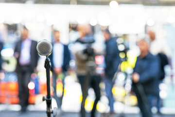 Microphone in focus against blurred journalists, reporters and camera operators at news conference or media event. Public relations - PR or journalism concept. - obrazy, fototapety, plakaty