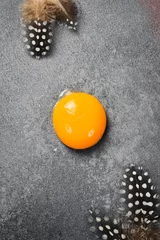 Poster Raw chicken egg yolk. Free space for text. On a gray stone background. © Yaruniv-Studio