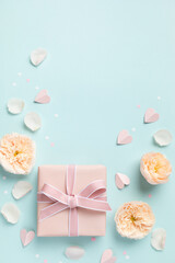 Lovely greeting card for Birthday, Woman or Mothers Day. Pink hearts, rose flowers and gift box on blue pastel table top view. Flat lay. - 774782925