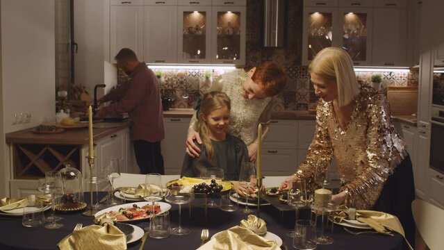 Slow motion shot footage of little girl helping her parents and granny with dining table setting for Christmas
