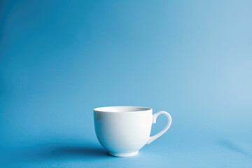 Obraz na płótnie Canvas A single white coffee cup against a solid blue background