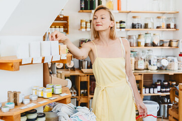 Smiling woman buying personal hygiene products in zero waste shop. Young girl choose cosmetics in local store.