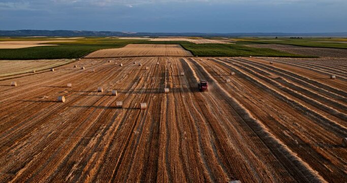 Tractor baler in action on a harvested wheat field