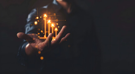 Businessman holding a growth arrow and market graph with glowing icons on a dark background. Man hand pointing to rising business chart, financial strategy concept on black background.