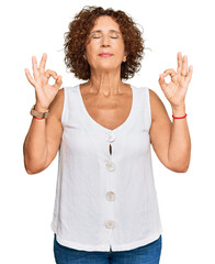 Beautiful middle age mature woman wearing casual white shirt relax and smiling with eyes closed doing meditation gesture with fingers. yoga concept.