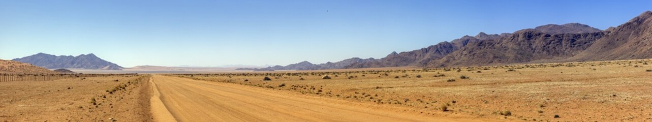 Picture of a gravel road on the edge of the Namib Naukluft National Park in Namibia against a blue...