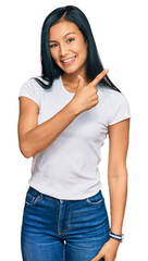 Beautiful hispanic woman wearing casual white tshirt cheerful with a smile on face pointing with hand and finger up to the side with happy and natural expression