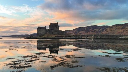 Drone view of Eilean Donan Castle during low-level flight over water