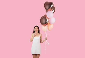 Excited woman with mouth open holding balloons