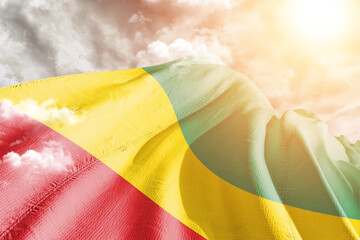 Guinea national flag cloth fabric waving on beautiful cloudy Background.