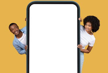Couple holding a large smartphone mockup vertically - obrazy, fototapety, plakaty