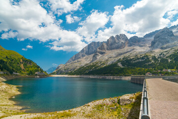 The famous lake named "Fedaia", in the Dolomites mountain chain, Italy. On the background the mountain named "Marmolada", with blue sky and white clouds.