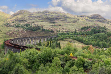 The Glenfinnan Viaduct curves gracefully amidst verdant highlands, showcasing Scotland rugged...