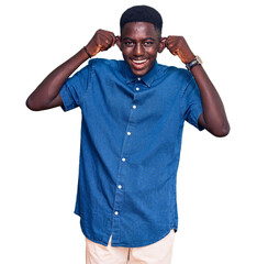 Young african american man wearing casual clothes smiling pulling ears with fingers, funny gesture....