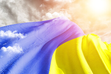 Ukraine national flag cloth fabric waving on beautiful cloudy Background.