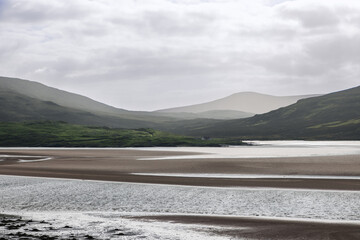 A tranquil view of the Kyle of Durness, showcasing a vast, shallow bay with intricate sandbanks and...