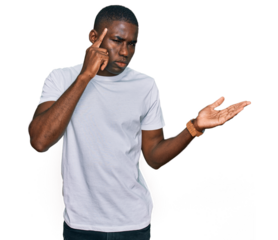 Young african american man wearing casual white t shirt confused and annoyed with open palm showing copy space and pointing finger to forehead. think about it.