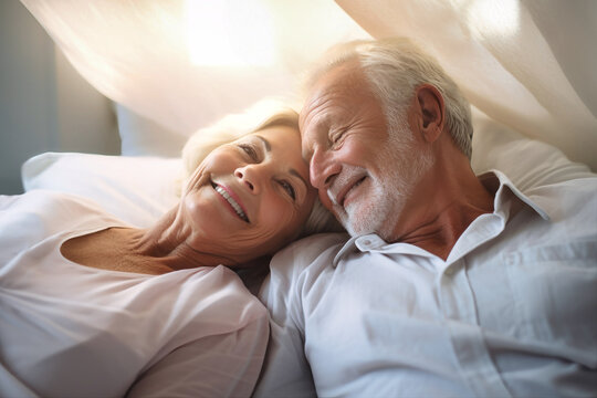 An elderly man and woman, a loving couple, are peacefully laying in a bed together, showing affection and love