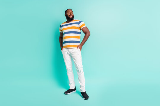 Full length photo of positive dreamy man wear striped t-shirt looking empty space isolated turquoise color background