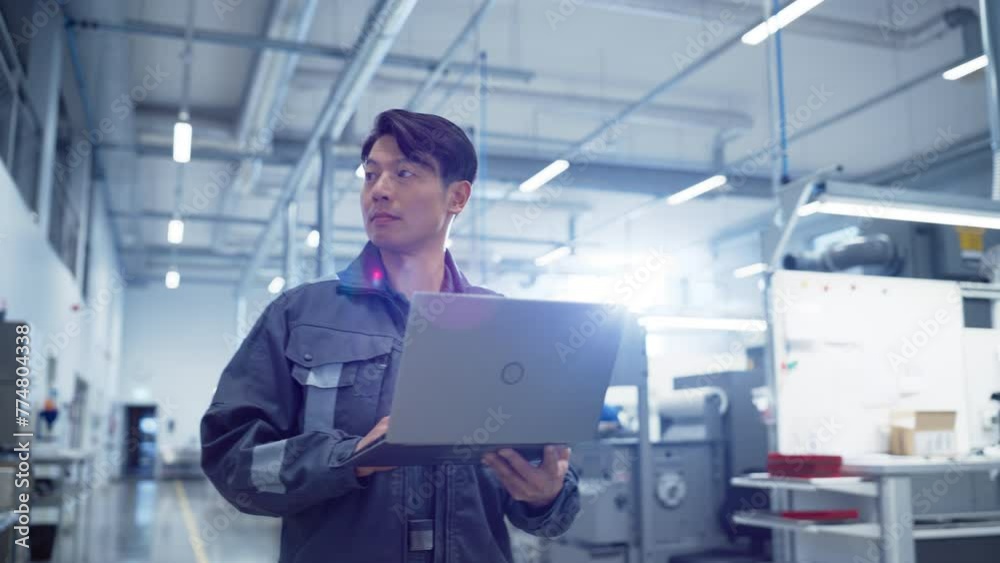 Poster focused asian engineer walking and using a laptop computer at electronics manufacturing factory. adu