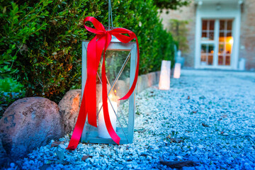 candle lantern with red ribbon along a garden pathway at dusk