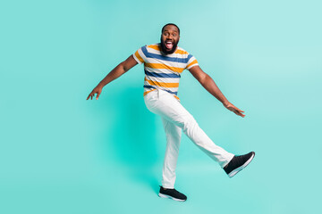 Full length photo of positive carefree man wear striped t-shirt dancing isolated teal color background