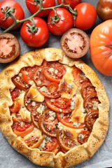 Tasty galette with tomato and cheese (Caprese galette) on parchment, top view
