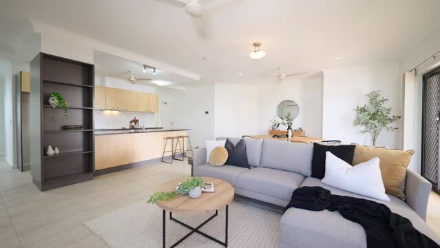 Grey Sectional Couch in Small Apartment with Open Plan Kitchen Dining and Lounge areas. Interior of house home for real estate property.