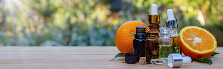bottle of aromatic essence and fresh orange on the background of nature.