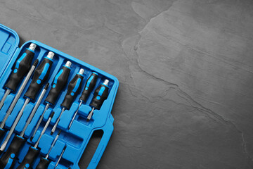 Set of screwdrivers in open toolbox on dark textured table, top view. Space for text