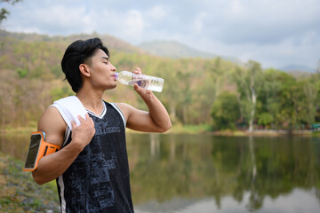 Shot of male runner resting and drinking water from a bottle for hydration after exercising