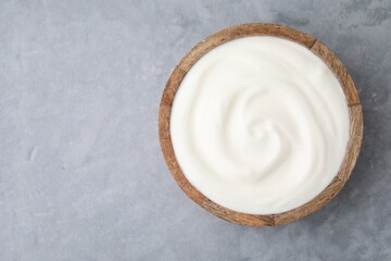 Delicious natural yogurt in bowl on grey table, top view. Space for text