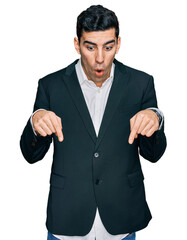 Handsome hispanic man wearing business clothes pointing down with fingers showing advertisement, surprised face and open mouth
