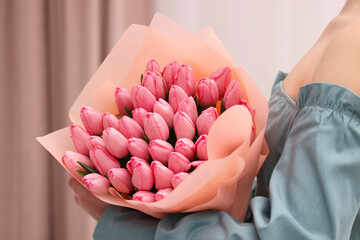 Woman holding bouquet of pink tulips indoors, closeup - obrazy, fototapety, plakaty