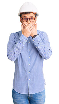 Handsome young man with bear wearing architect hardhat shocked covering mouth with hands for mistake. secret concept.
